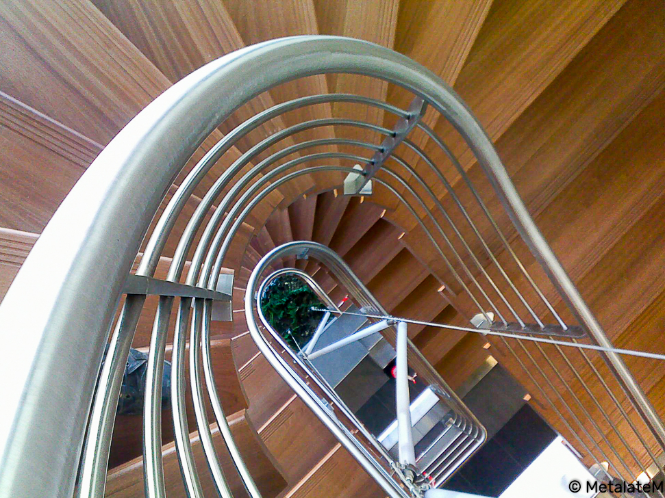 Escalier sur plusieurs niveaux avec rampe continue inox et marches en bois.